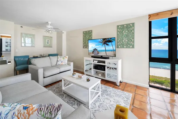a living room with furniture a flat screen tv and a floor to ceiling window