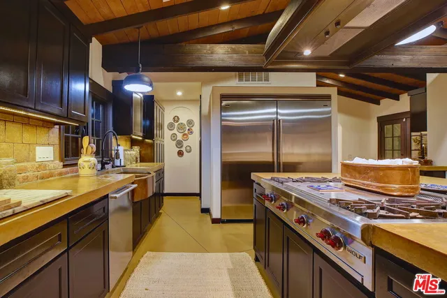 a room with stainless steel appliances kitchen island granite countertop a table chairs and a refrigerator