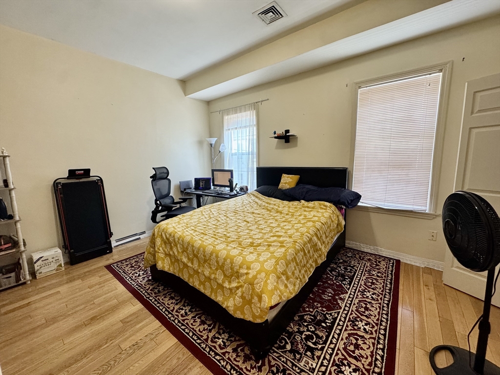 22 Elmore Street, Unit 2 Boston, MA 02119 - Photo 11 of 17 a bed sitting in a bedroom next to a window with chair and dresser