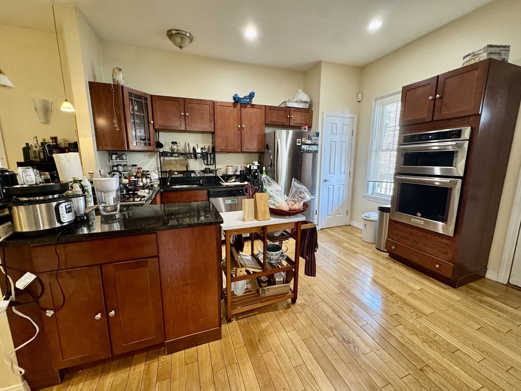 22 Elmore Street, Unit 2 Boston, MA 02119 - Photo 4 of 17 a kitchen with stainless steel appliances wooden floors wooden cabinets and sink