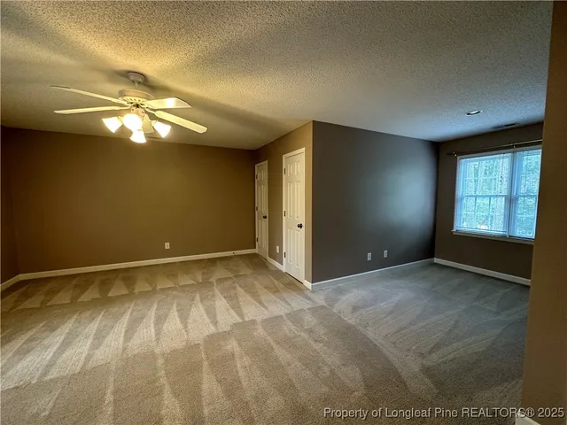 a view of an empty room with window and chandelier fan