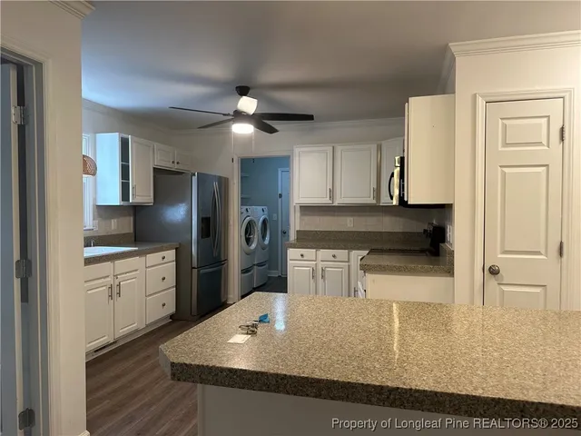 a kitchen with stainless steel appliances granite countertop a refrigerator a sink dishwasher a stove and white cabinets with wooden floor