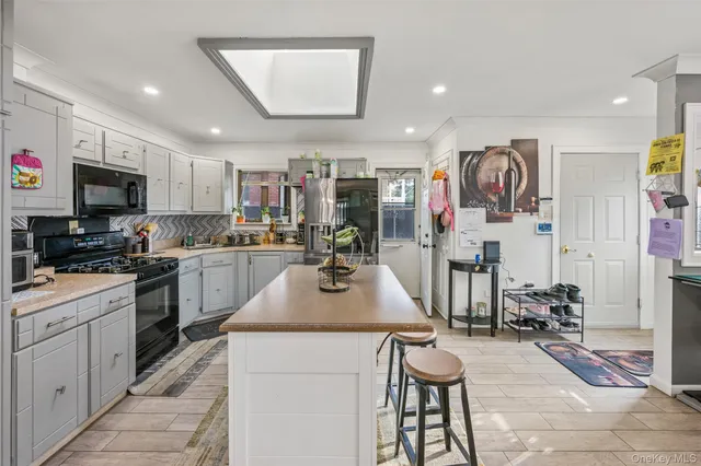 a kitchen with stainless steel appliances kitchen island granite countertop a table chairs and a refrigerator