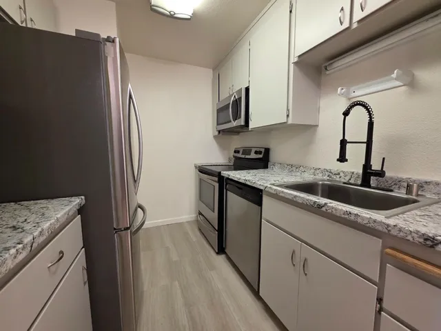a kitchen with a sink a refrigerator and cabinets
