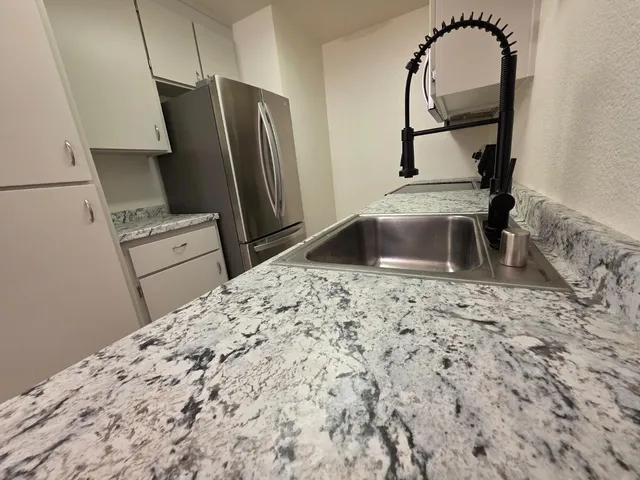 a kitchen with granite countertop a refrigerator and a sink