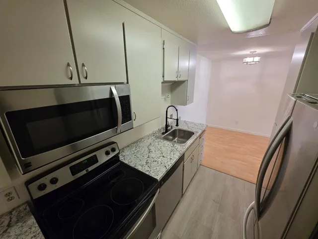 a kitchen with stainless steel appliances granite countertop a stove a sink and a microwave
