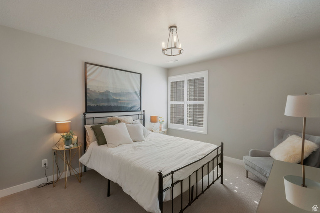 2319 North 3370 West Lehi, UT 84048 - Photo 23 of 30 Carpeted bedroom featuring neutral wall tones, a window with white plantation shutters, and a modern chandelier