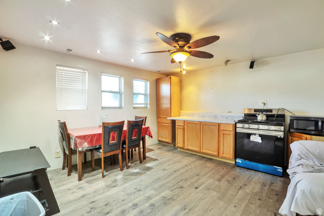 1057 North 700 West Clinton, UT 84015 - Photo 10 of 15 Kitchen with stainless steel gas stove, light countertops, light wood-style floors, black microwave, and ceiling fan