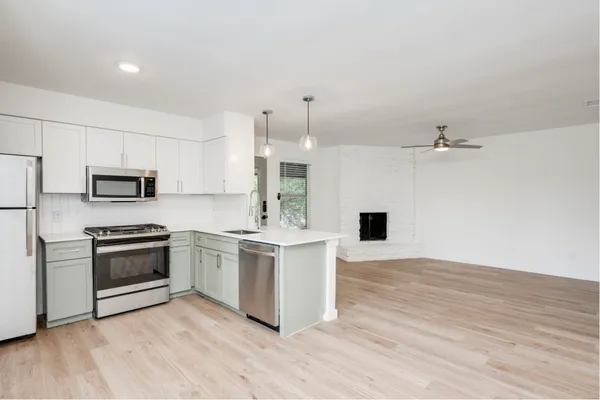 a kitchen with stainless steel appliances a stove top oven a sink and a refrigerator