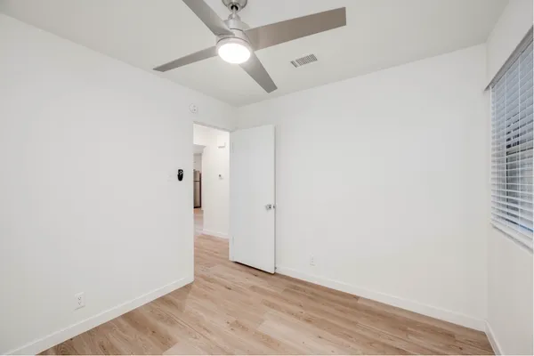 an empty room with a ceiling fan and a window