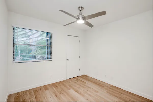an empty room with a window and a ceiling fan