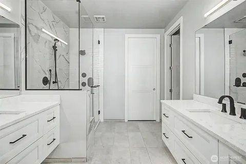 a bathroom with a double vanity sink mirror and shower