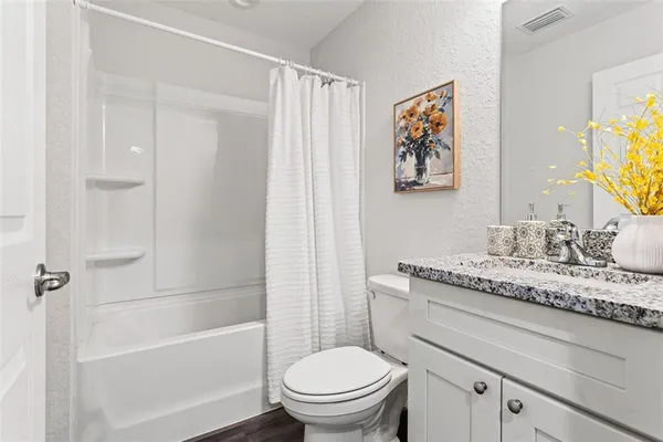 a bathroom with a granite countertop toilet a sink and a bathtub