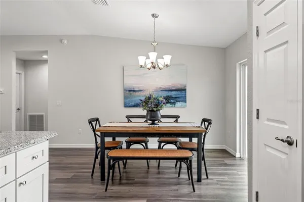 a dining room with furniture wooden floor a chandelier and a mirror
