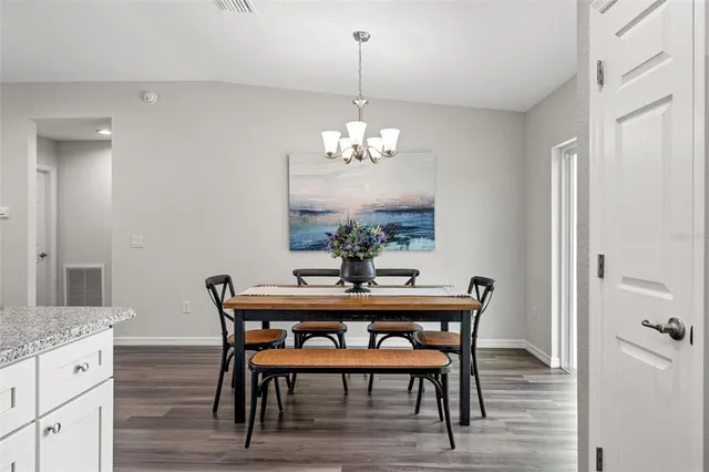 a dining room with furniture wooden floor a chandelier and a mirror