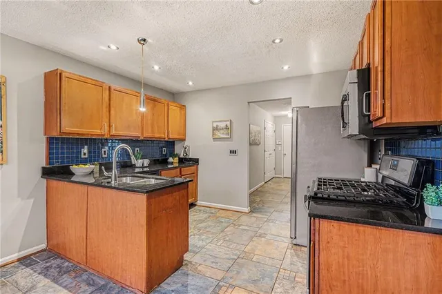 a kitchen with stainless steel appliances granite countertop a stove a sink and a refrigerator