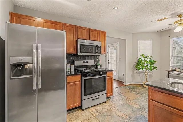 a kitchen with stainless steel appliances granite countertop a refrigerator a stove and a sink