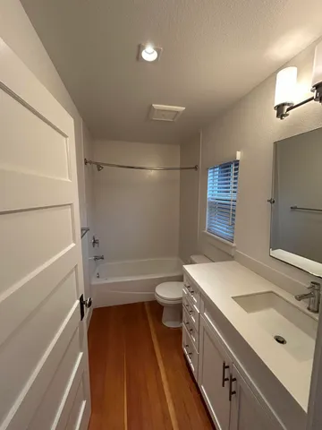 a bathroom with a tub sink vanity granite and toilet