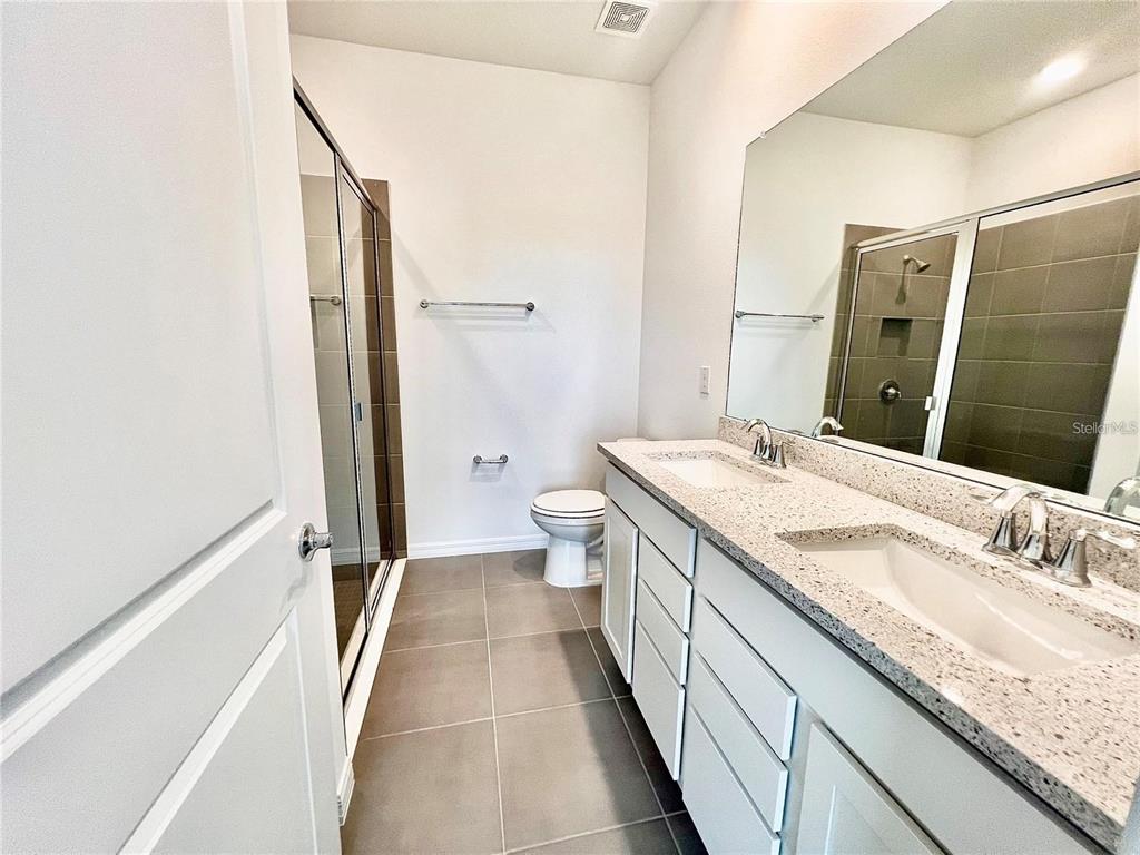 2373 Bending Bonsai Drive Wesley Chapel, FL 33543 - Photo 21 of 29 a bathroom with a granite countertop sink a toilet a mirror and shower