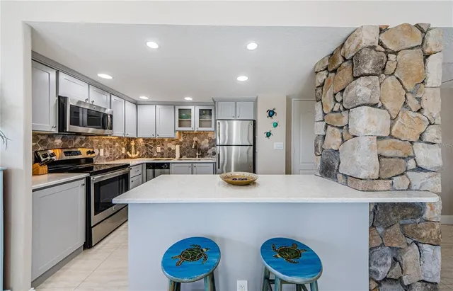 a kitchen with stainless steel appliances granite countertop a sink a stove a refrigerator and a refrigerator