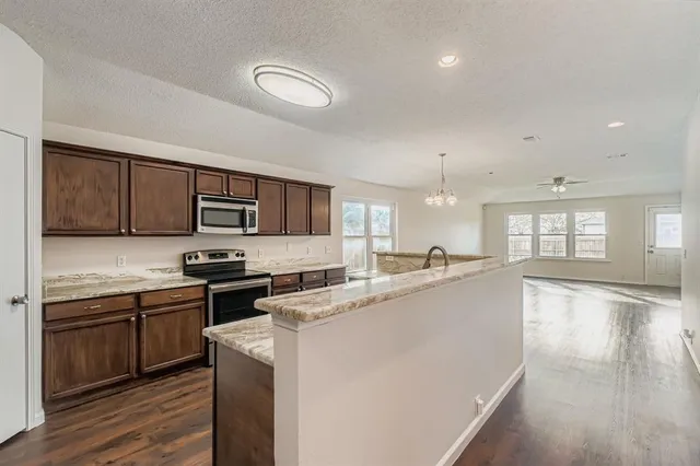 a large kitchen with stainless steel appliances granite countertop a stove sink and cabinets
