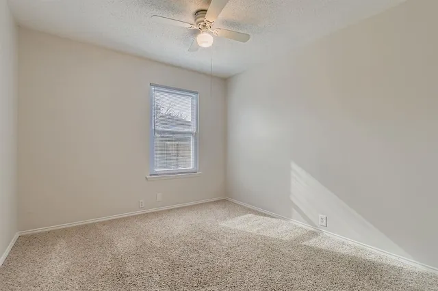 an empty room with a window and ceiling fan