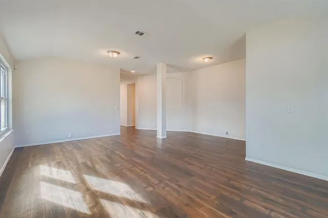 a view of an empty room with wooden floor