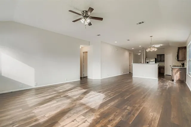 a view of an empty room with kitchen appliances and a ceiling fan