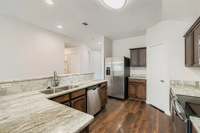a kitchen with stainless steel appliances granite countertop a sink stove and refrigerator