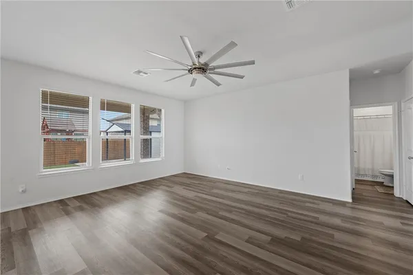 a view of empty room with wooden floor and fan