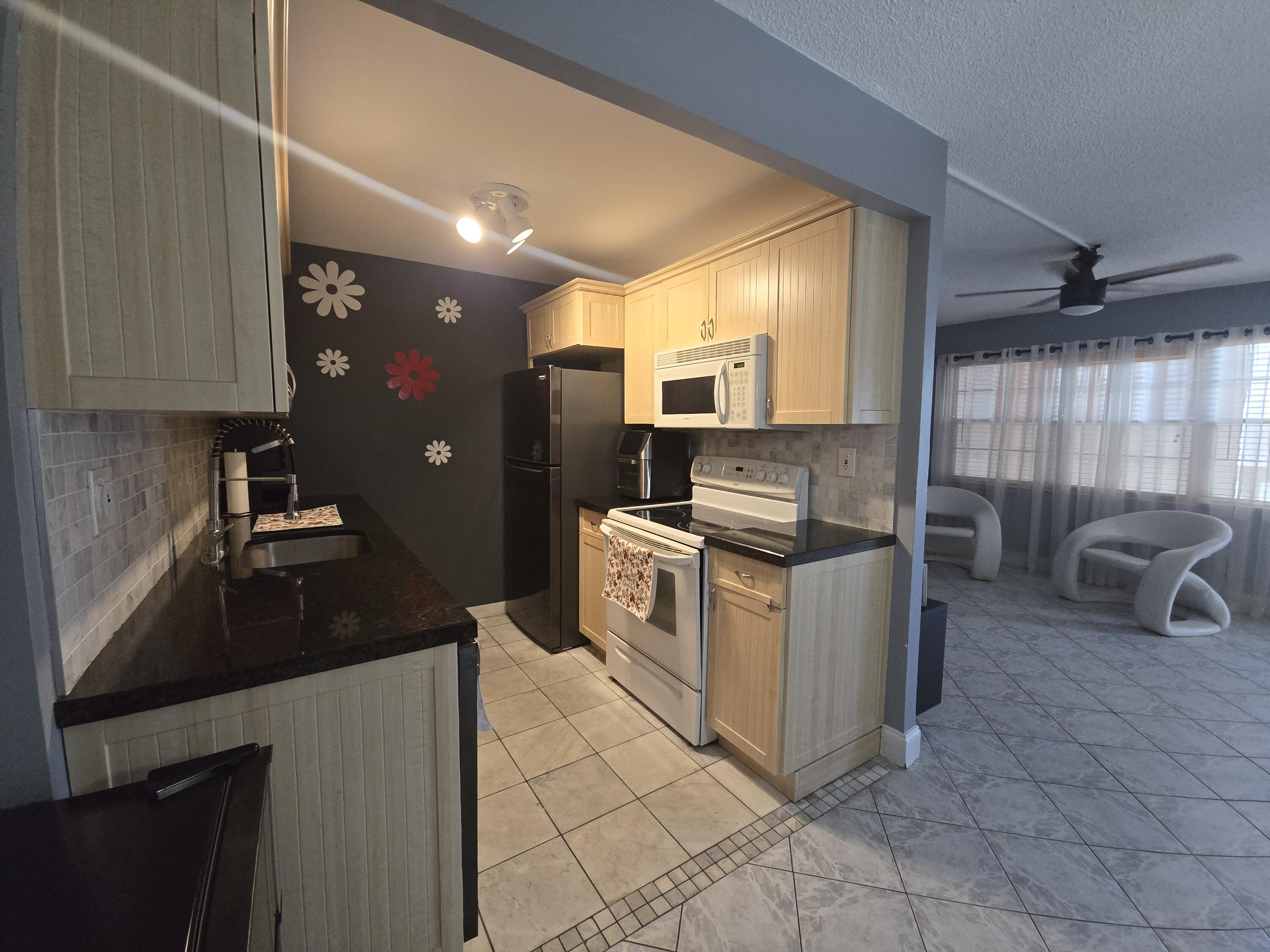 2010 Westbury F, Unit 2010 Deerfield Beach, FL 33442 - Photo 16 of 28 a kitchen with stainless steel appliances granite countertop a sink stove and refrigerator