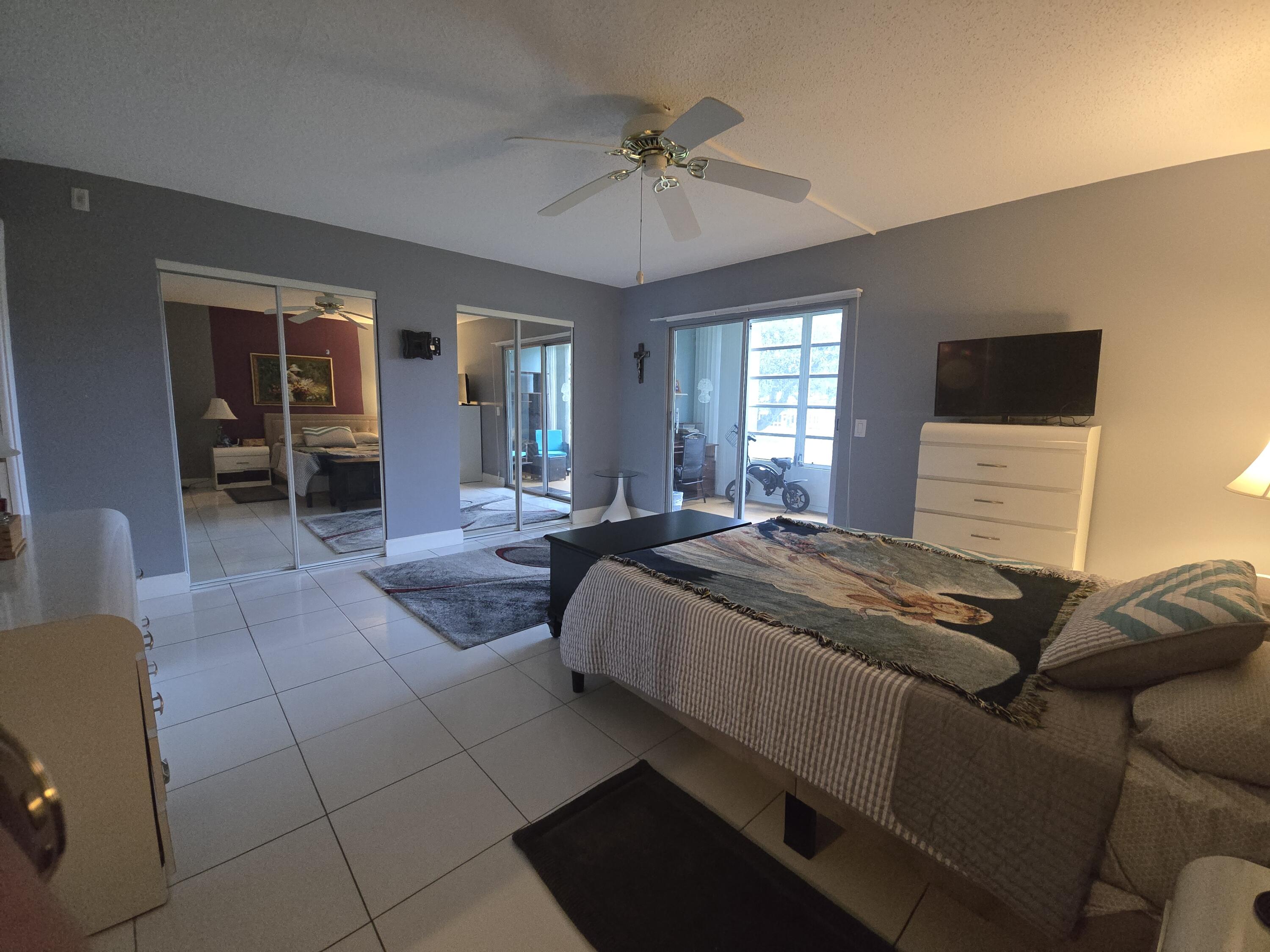 2010 Westbury F, Unit 2010 Deerfield Beach, FL 33442 - Photo 22 of 28 a bedroom with a bed and a chandelier