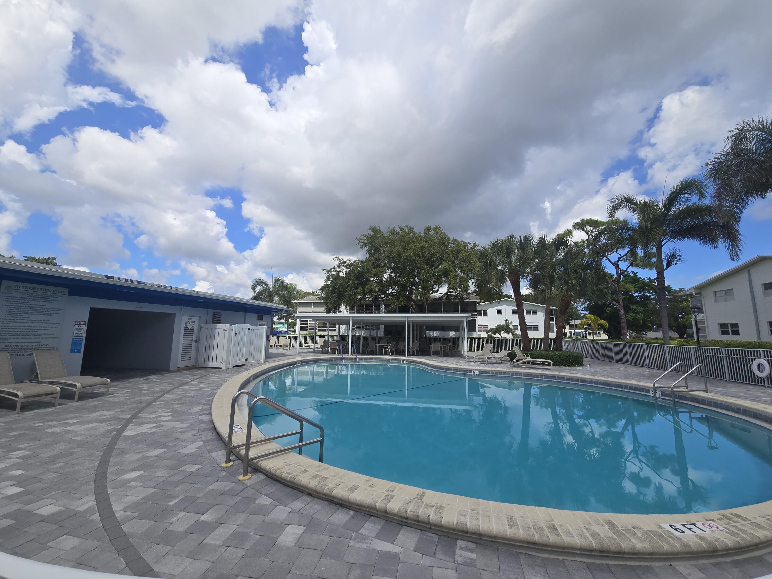 2010 Westbury F, Unit 2010 Deerfield Beach, FL 33442 - Photo 9 of 28 a swimming pool with outdoor seating and barbeque oven
