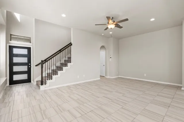 a view of an empty room with wooden floor and a ceiling fan