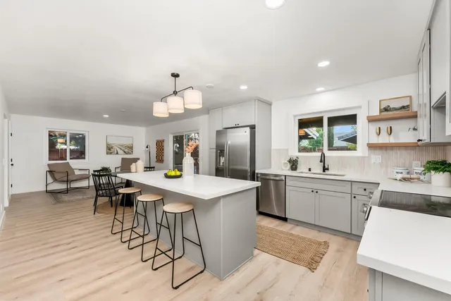 a kitchen with stainless steel appliances granite countertop table chairs sink and cabinets