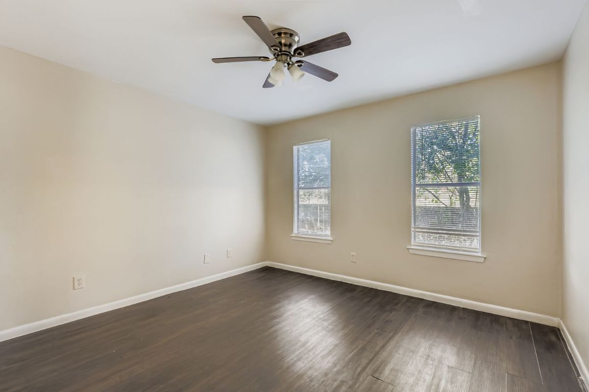 2005 West Loop, Unit A Austin, TX 78758 - Photo 8 of 11 an empty room with wooden floor chandelier fan and windows
