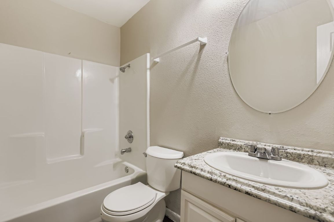2005 West Loop, Unit A Austin, TX 78758 - Photo 9 of 11 a bathroom with a granite countertop sink toilet and shower