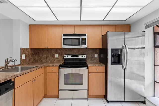 a kitchen with stainless steel appliances granite countertop a refrigerator a sink a stove top oven and a dishwasher