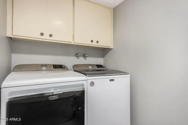 a view of washer and dryer with white cabinets