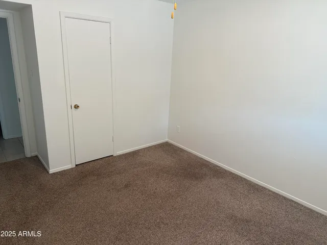 an empty room with a chandelier fan and closet