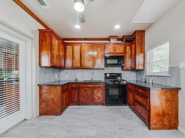 a large kitchen with stainless steel appliances granite countertop a stove sink and cabinets