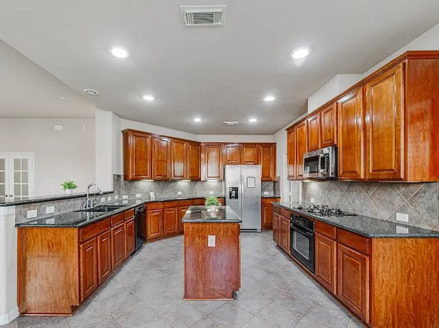 a kitchen with stainless steel appliances granite countertop wooden cabinets a sink and a counter space