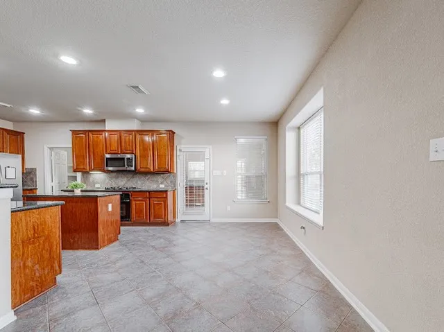 a large kitchen with stainless steel appliances granite countertop a stove and a sink