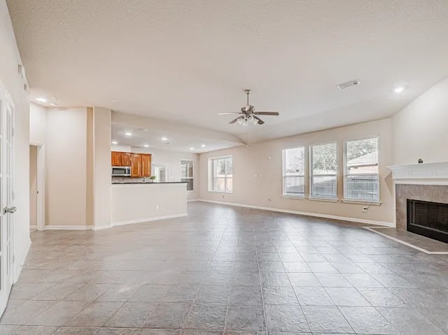 a view of an empty room with a kitchen and fireplace
