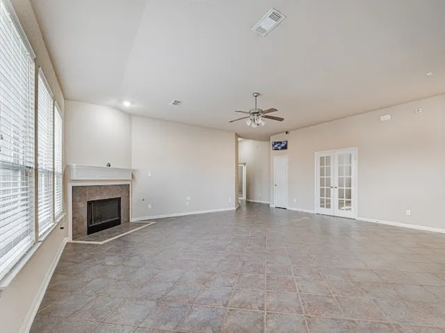 an empty room with fireplace fan and windows
