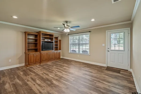 a view of an empty room with a window and wooden floor