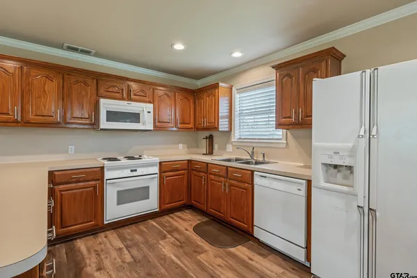 a kitchen with stainless steel appliances granite countertop wooden cabinets a sink a stove a refrigerator and island with wooden cabinets