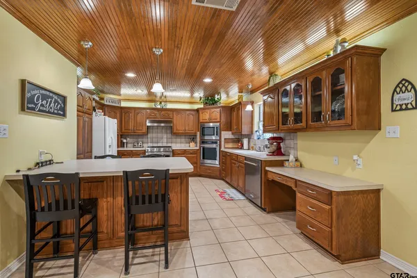 a kitchen with lots of wooden cabinets appliances and furniture