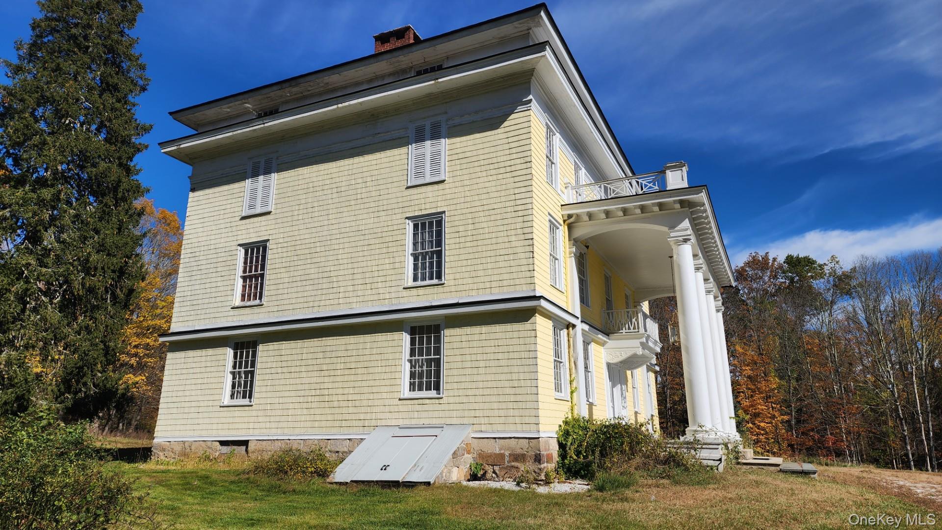 175 Waccabuc Road Goldens Bridge, NY 10526 - Photo 2 of 36 Rear view of house featuring a chimney, a balcony, and a lawn