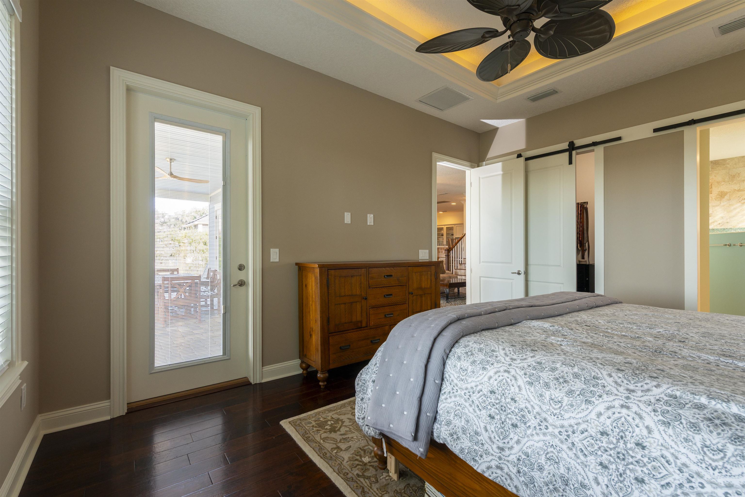 5475 Riverwood Road North St. Augustine, FL 32092 - Photo 16 of 62 Bedroom with a barn door, access to exterior, dark wood-style flooring, ceiling fan, and a raised ceiling